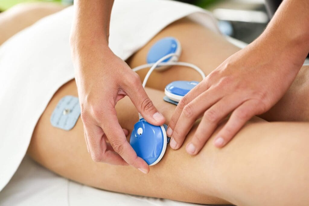 Pain Management Physiotherapy - Applying electro stimulation in physical therapy to a young woman leg.